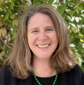 a person with long hair and a green necklace